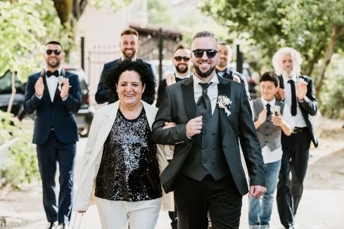 groom with his mother and family walking to the church