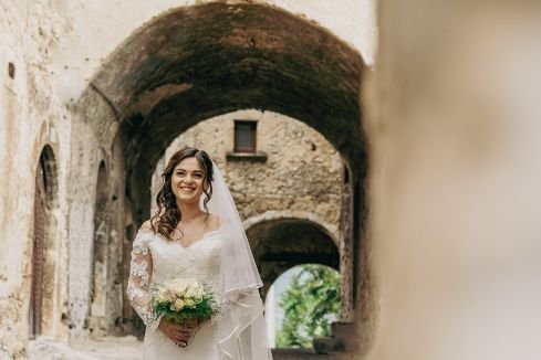 pretty young bride in her wedding dress walking through an old italian street