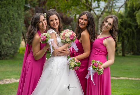 smiling bride with her smiling brides maids in a garden all holding flowers